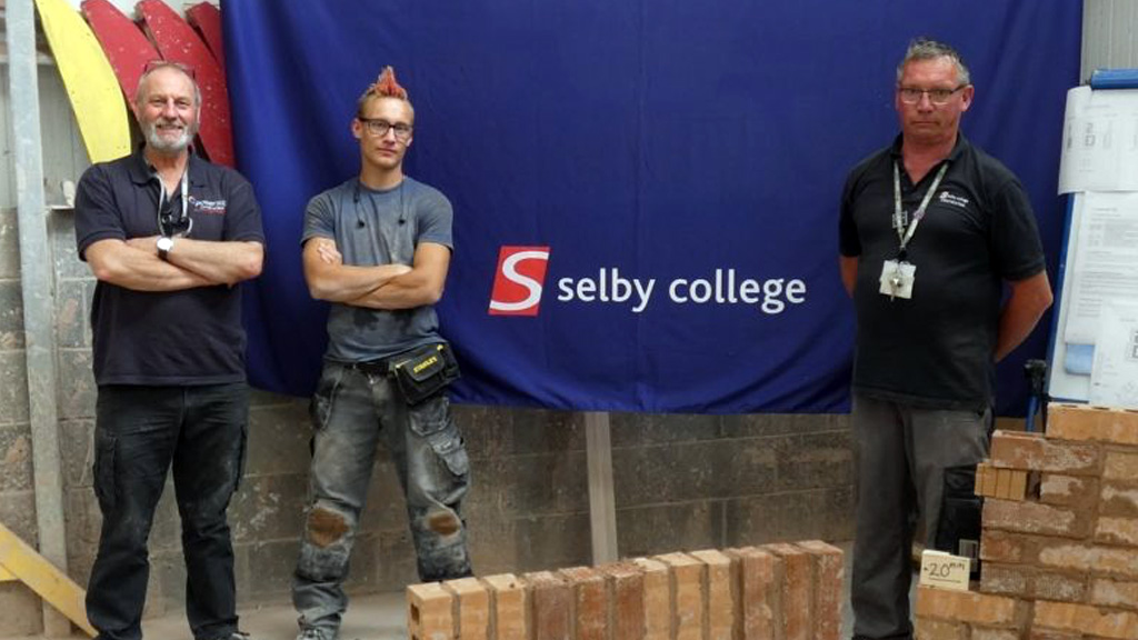 Bricklaying student with his tutors 
