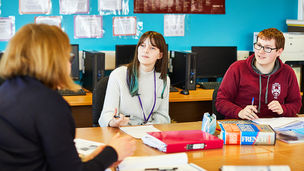 Two students in a classroom with a tutor