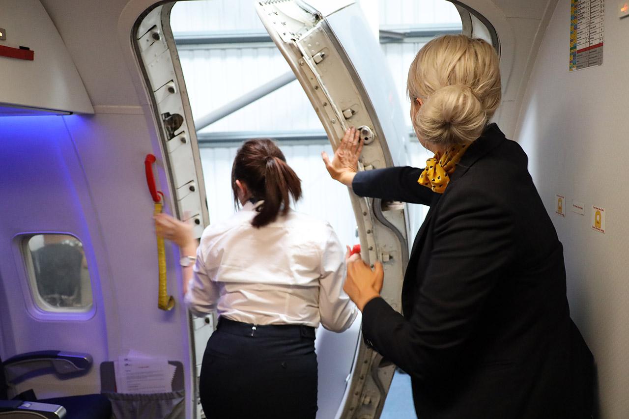 Travel and tourism students learning to close an airplane door.