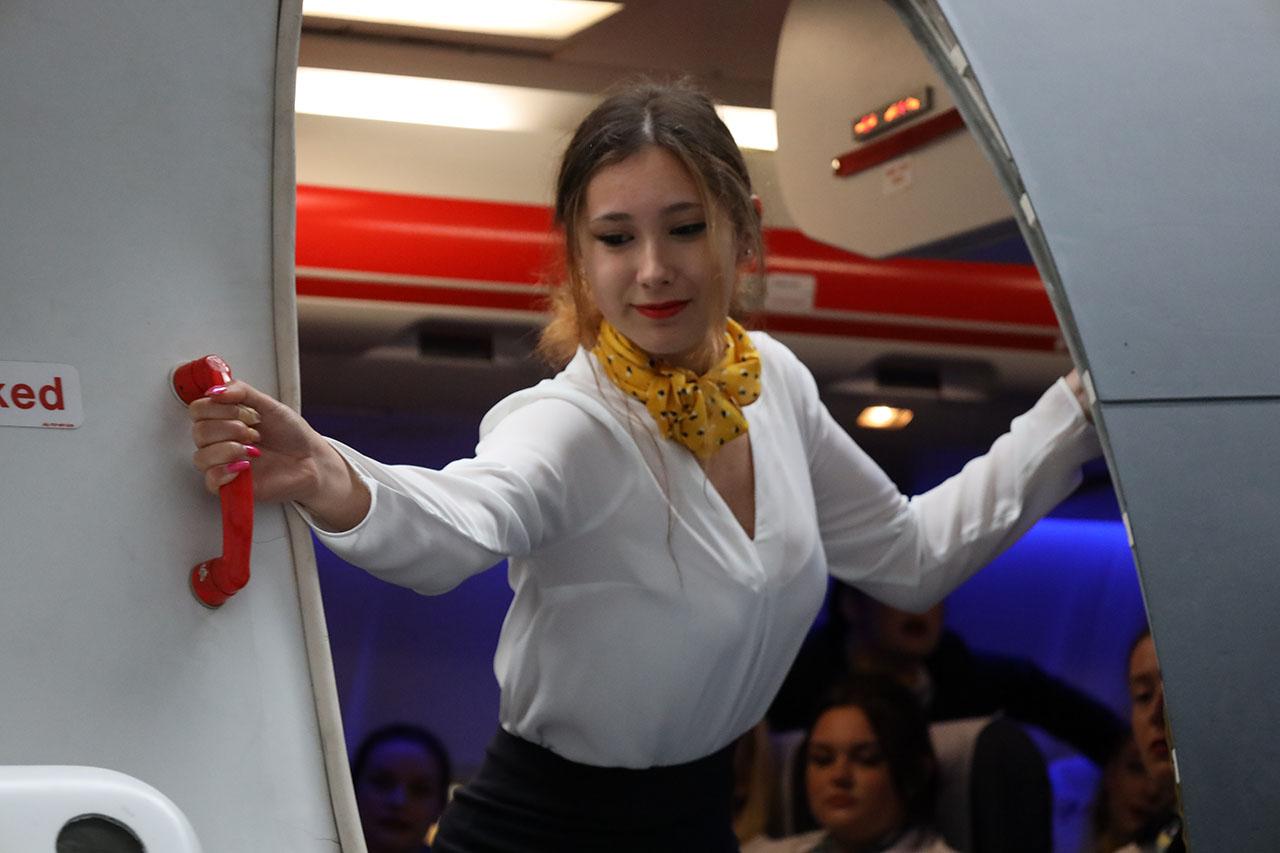 Travel and tourism students learning to close an airplane door.